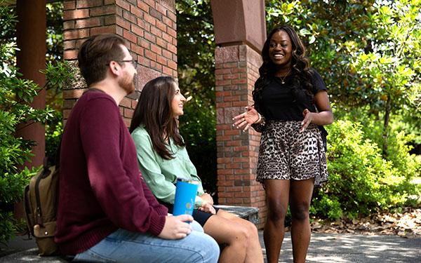 UWF students smile while chatting by the Canto al Sol archway.