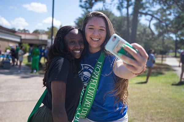 two students taking a selfie at a uwf homecoming event